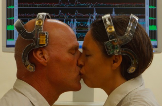 Twee mensen kussen elkaar terwijl ze een E.E.G. koptelefoon dragen.